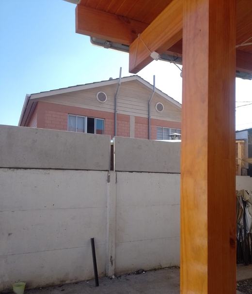Cierre de concreto vibrado junto a una pérgola de madera.