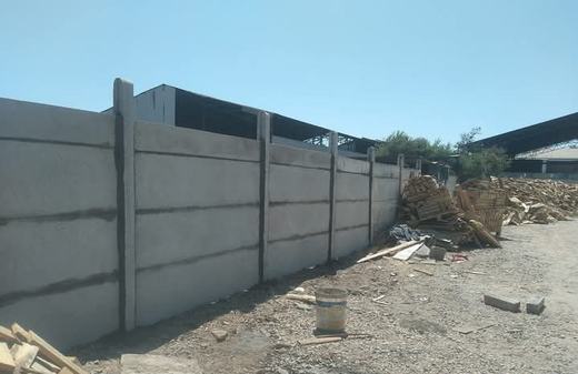 Cierre perimetral de concreto vibrado en un terreno en construcción.