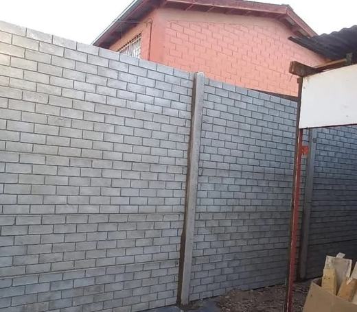 Muro perimetral de bloques de concreto junto a una vivienda.