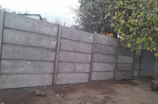 Cierre perimetral de concreto vibrado en la esquina de un terreno.