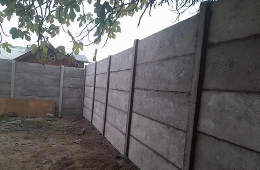Cierre perimetral de concreto vibrado rodeado de árboles.