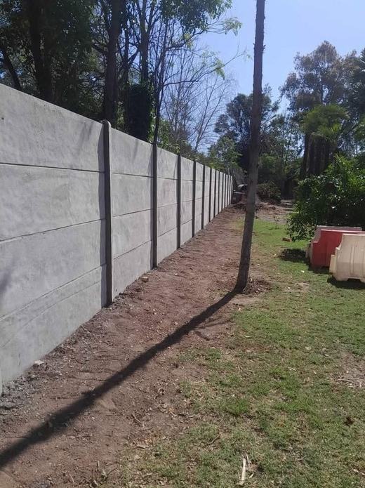 Cierre perimetral de concreto vibrado en un jardín.